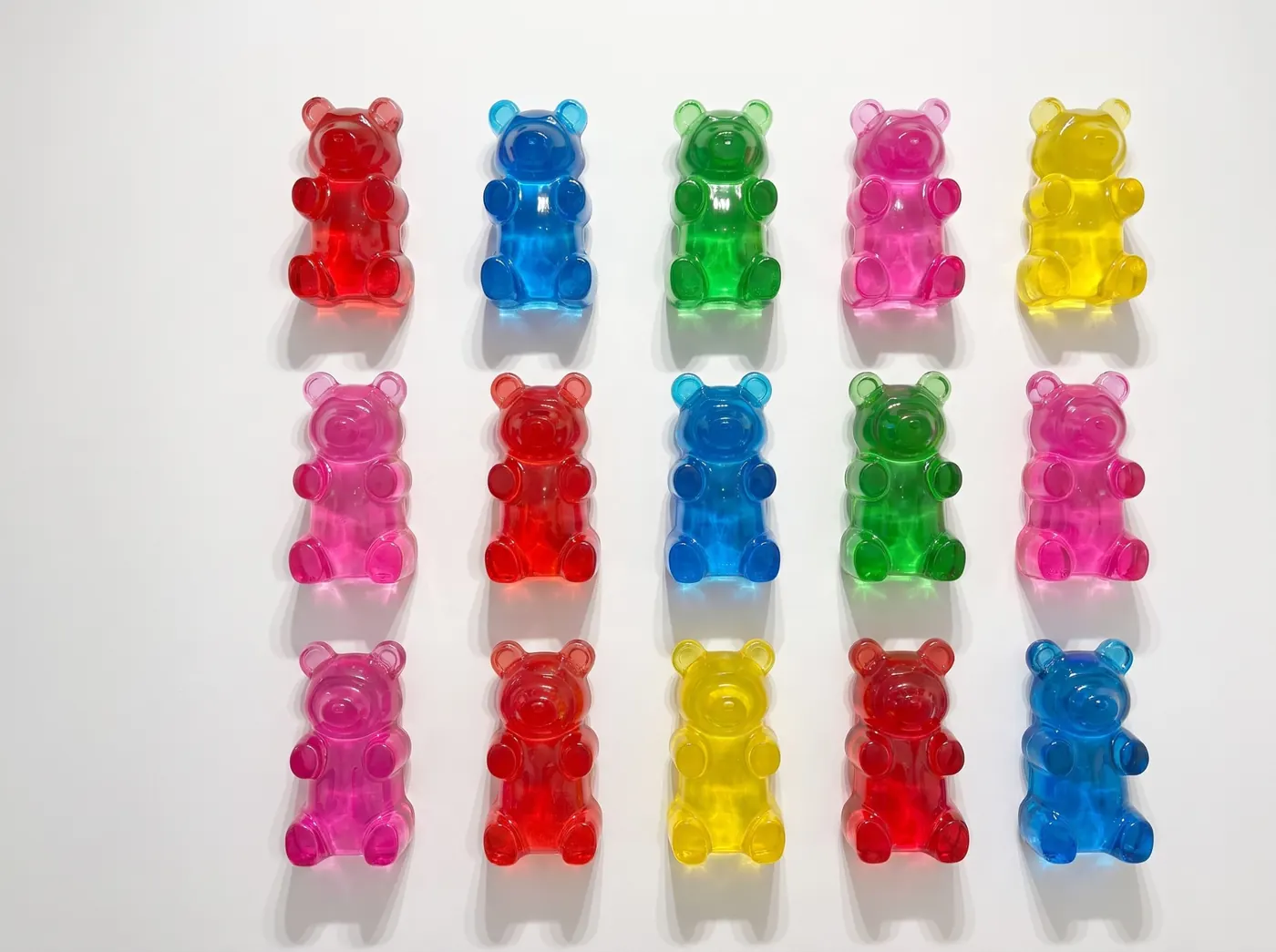 Quinze oursons bonbons de couleur accrochés à un mur blanc